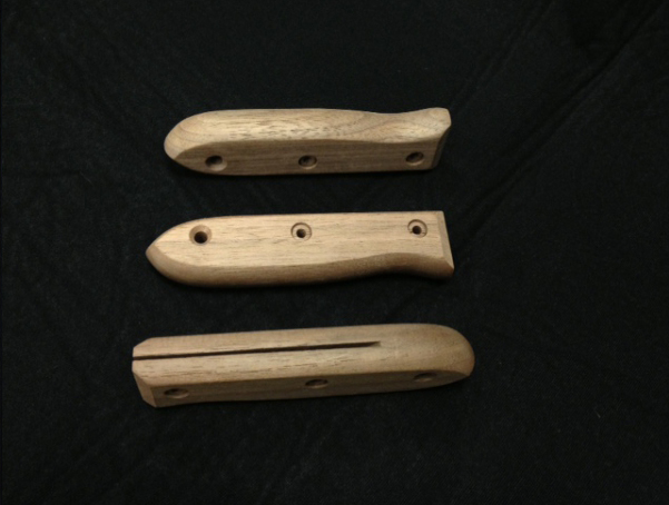 Three shaped wooden custom handles made out of walnut. They are all slotted and have three cross bored holes.